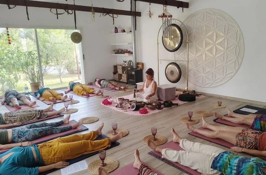 Participantes descansan durante un baño de gong y cuencos en una sala luminosa