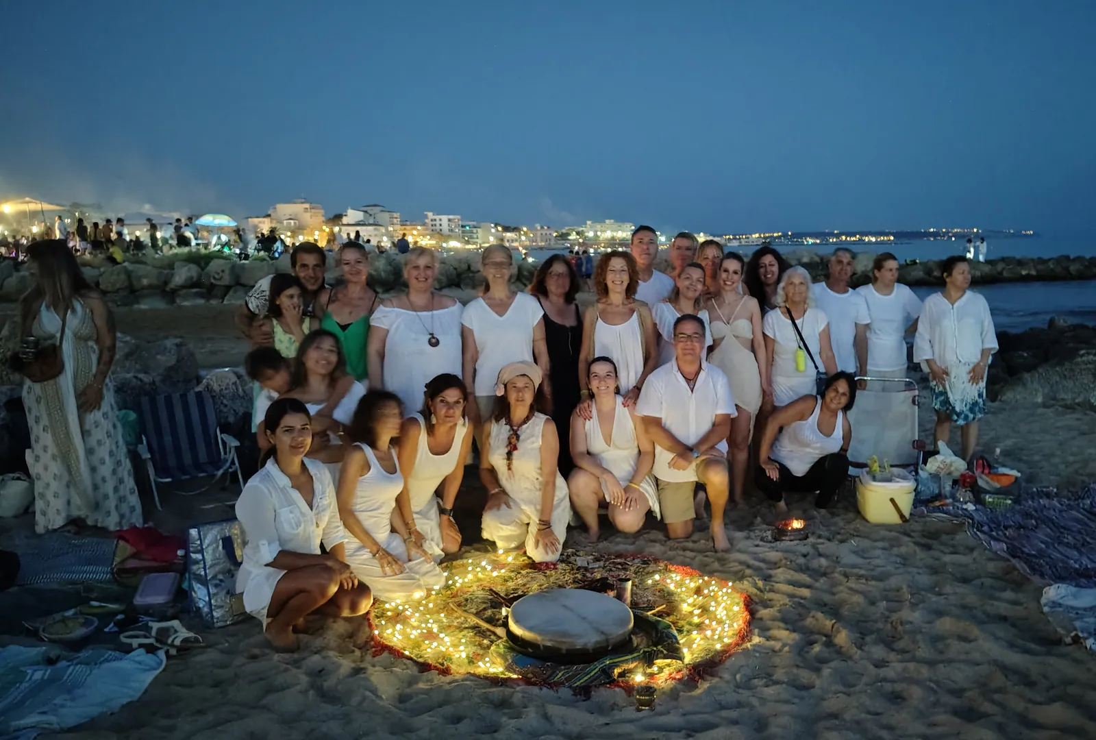 Participantes en un encuentro de celebración junto al mar al anochecer