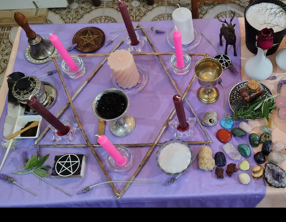 Altar preparado con velas, hierbas, flores y símbolos espirituales